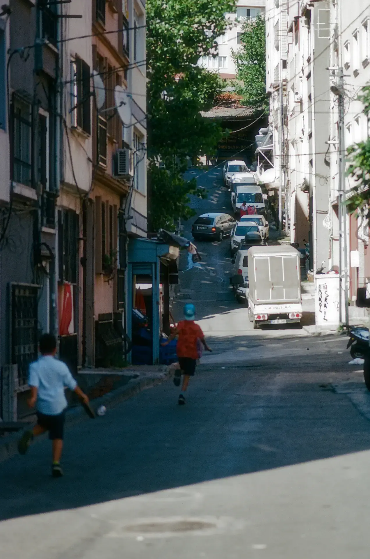 Two kids running in the street playing tag