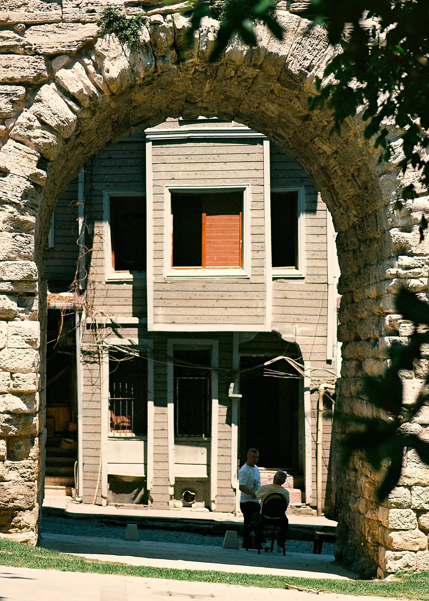 Two men conversing under an archway with a building in the background